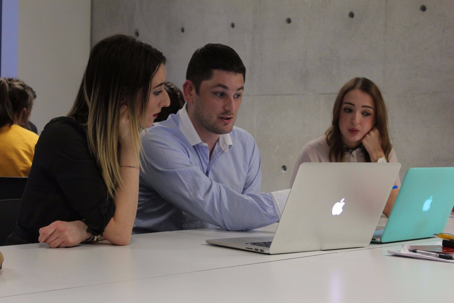 Three professionals conversing around a laptop