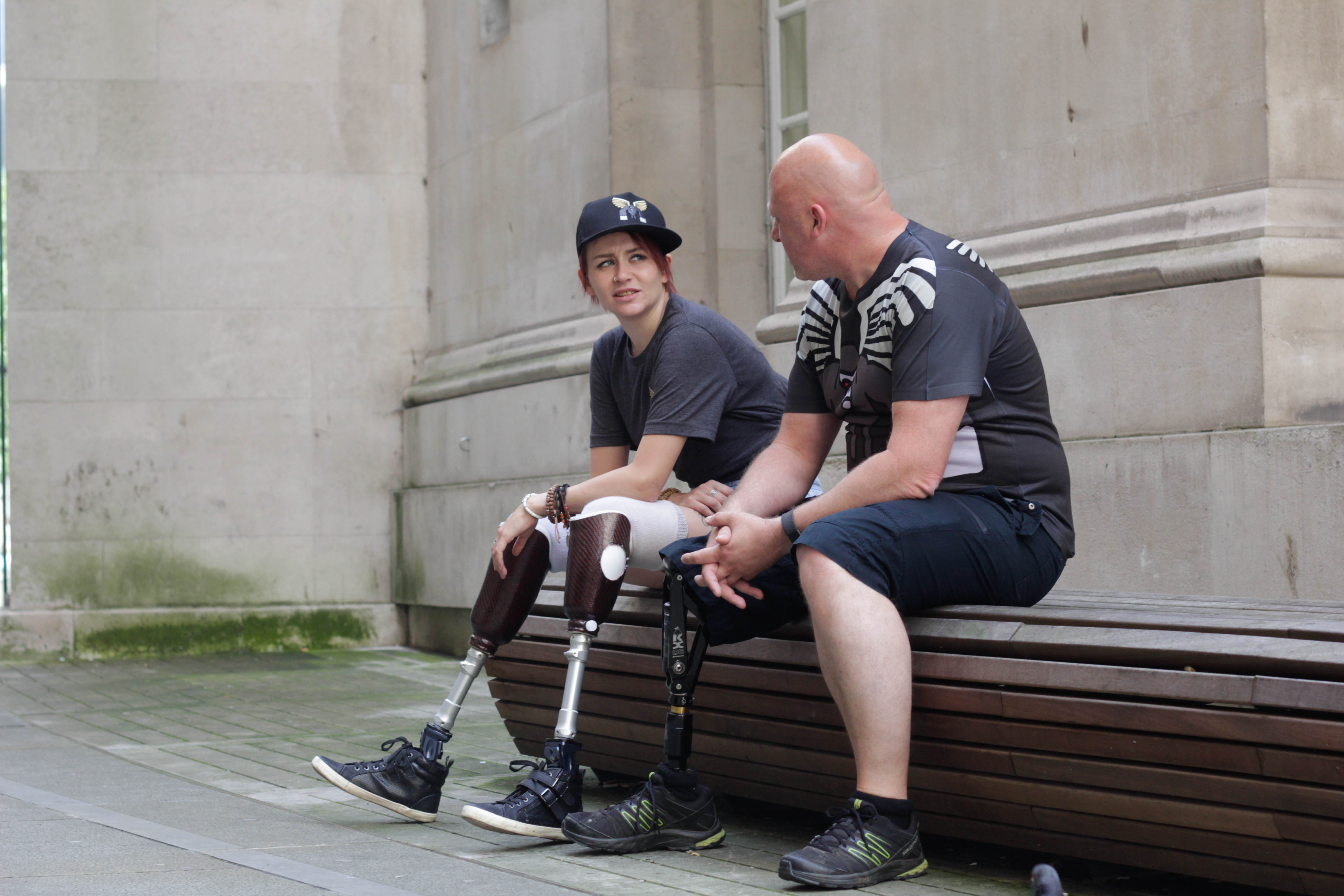 Two amputees sat on bench.