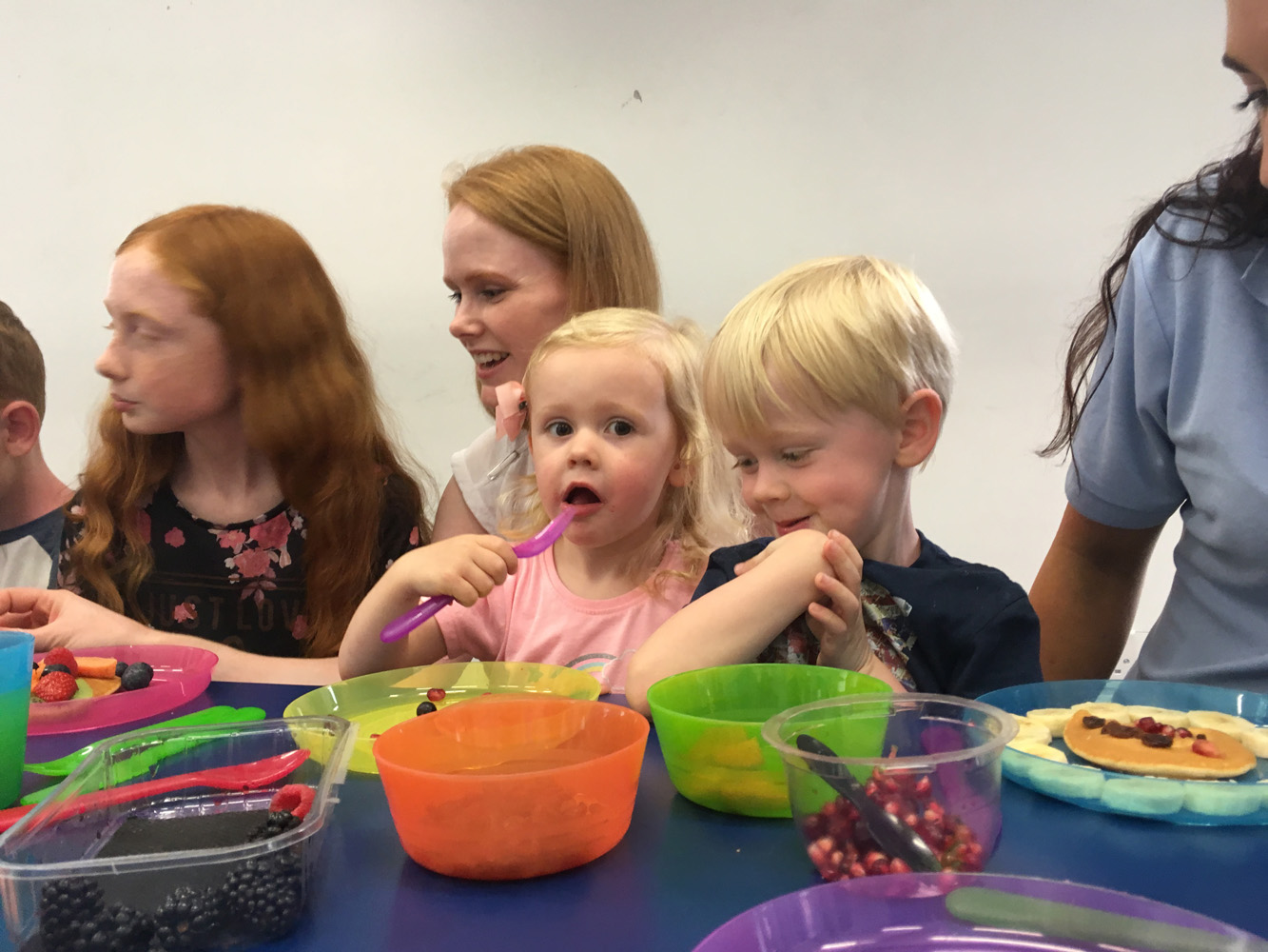 Little girl eating and boy smiling at food.