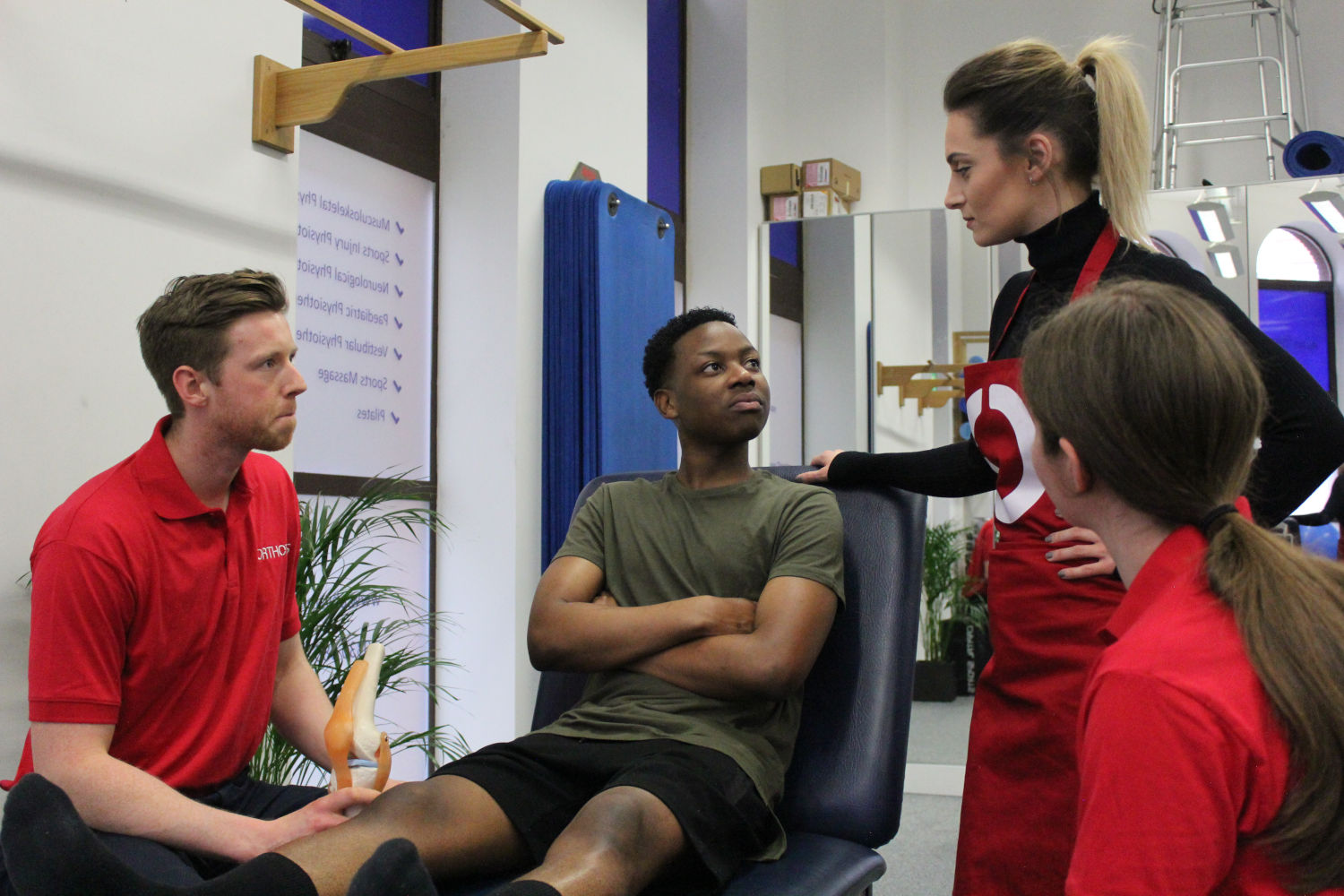 Three Orthotics therapists consulting a young patient.