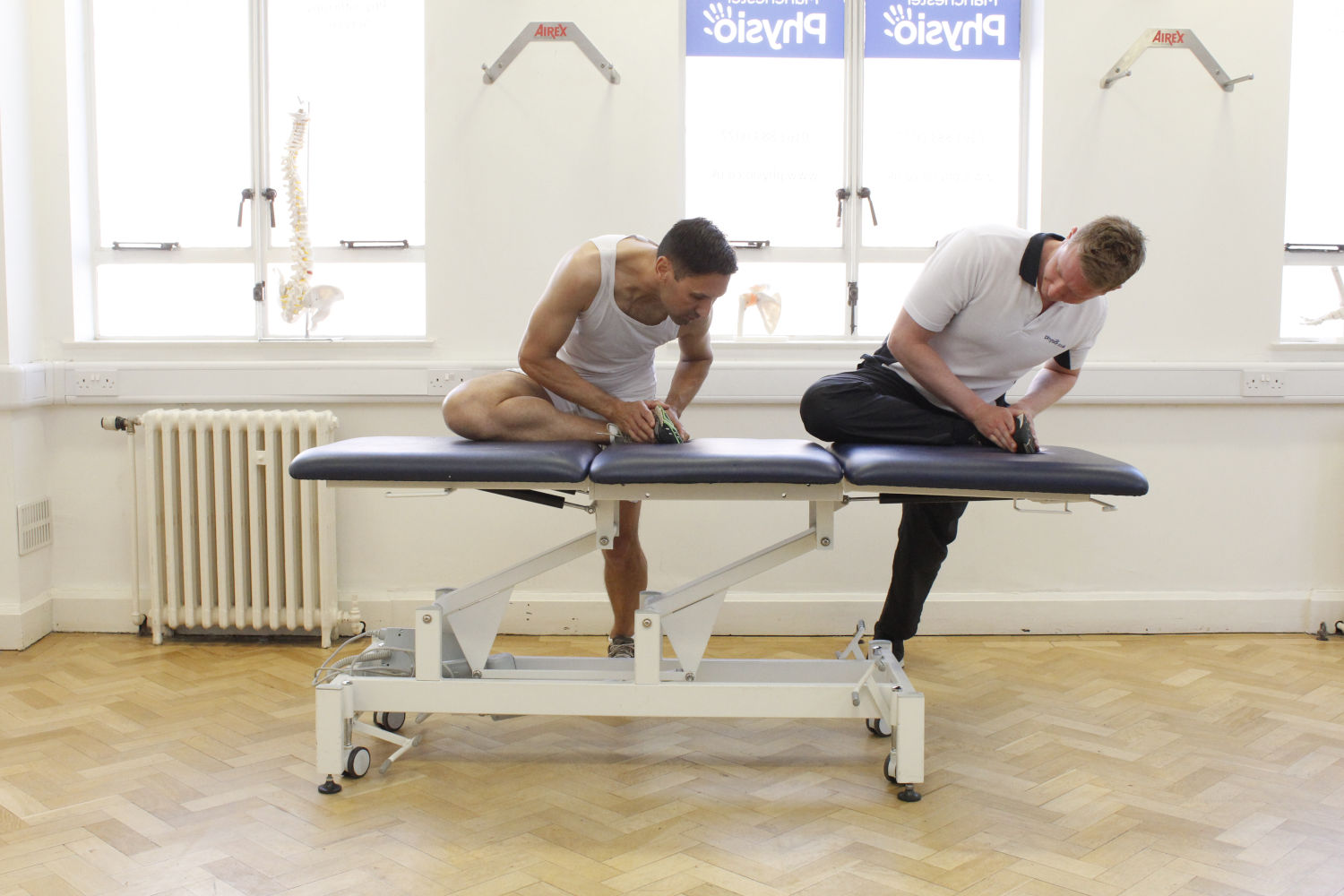 Physio and patient with legs on table.