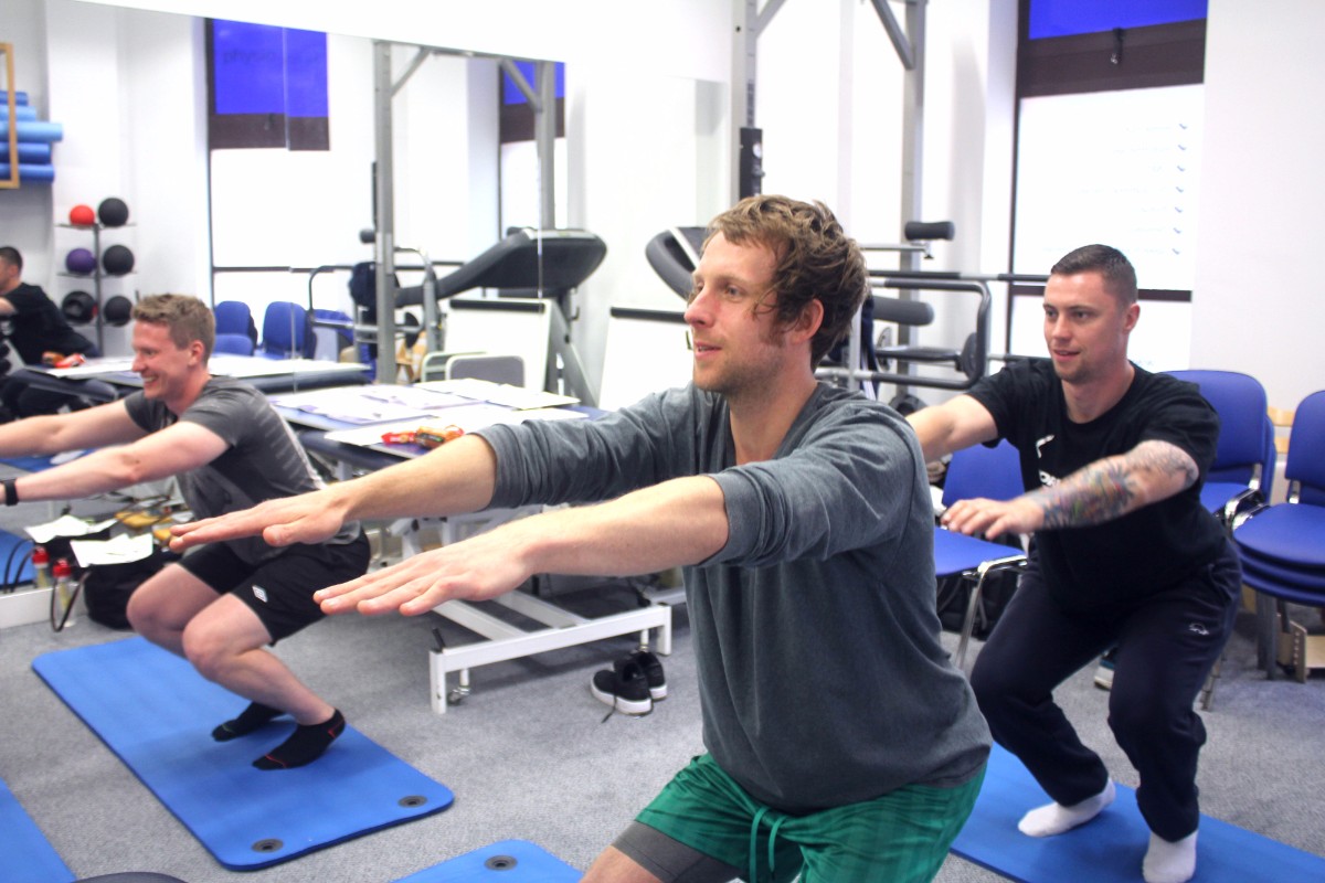 Three men performing squats.