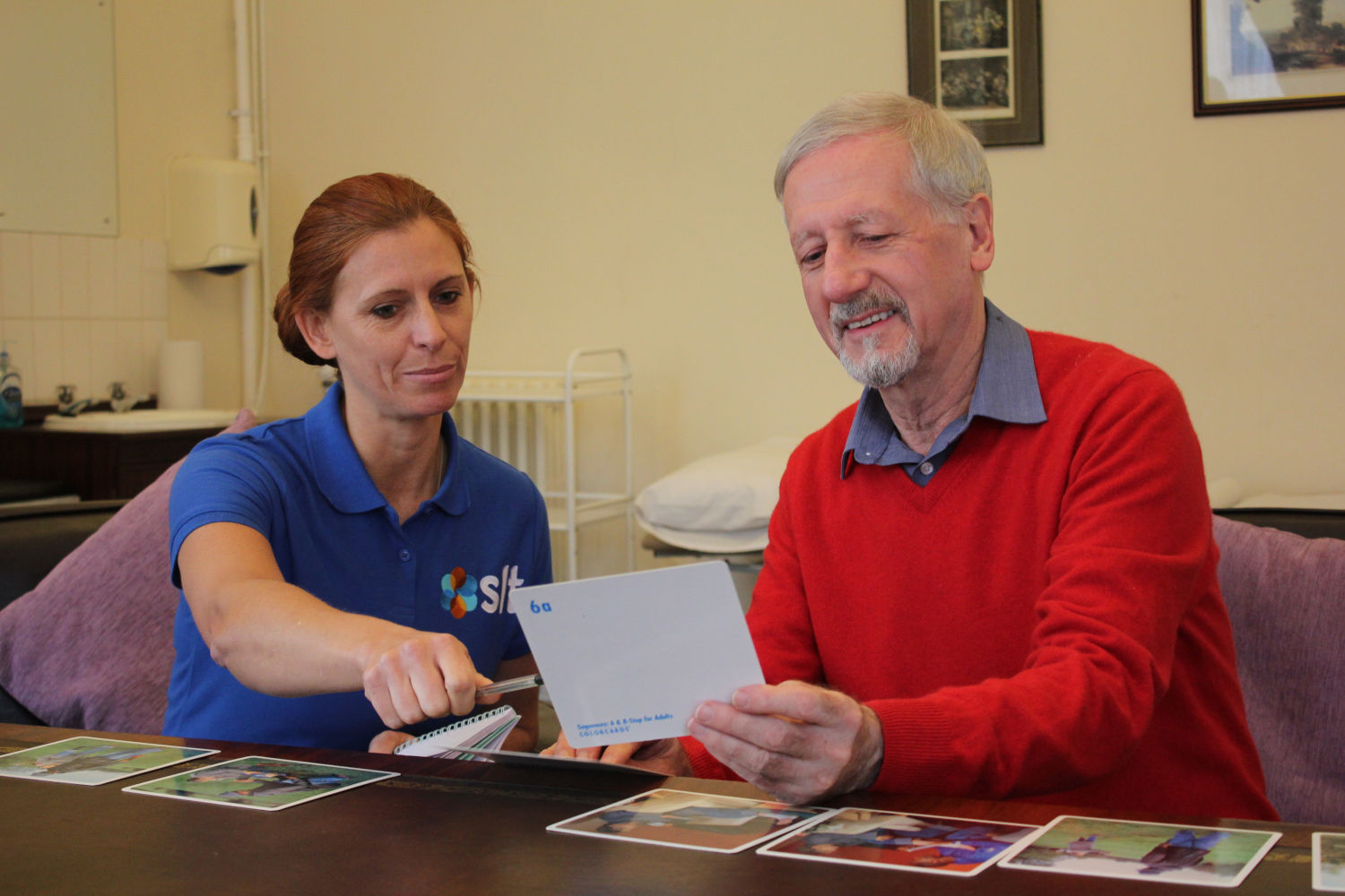 SLT therapist pointing to card in patient's hand.