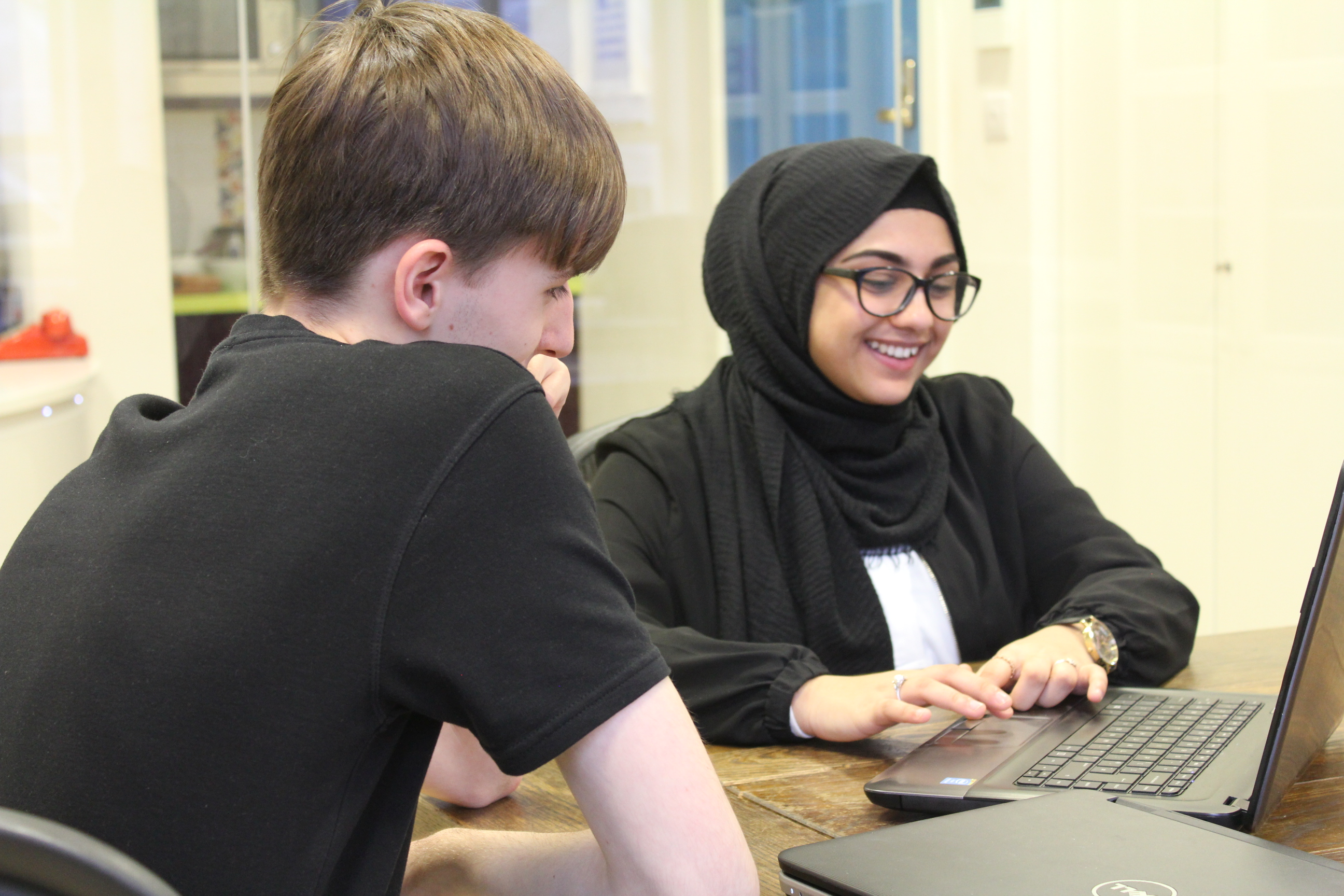 Two smiling Tx Group employees looking at laptop.